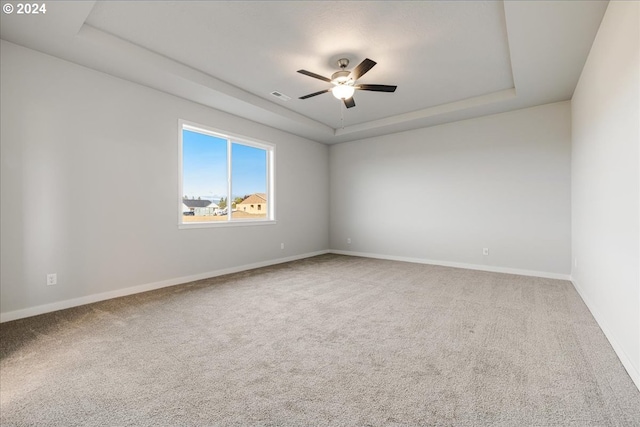 spare room with ceiling fan, carpet flooring, and a raised ceiling