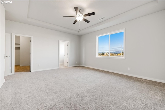 unfurnished bedroom featuring a spacious closet, ceiling fan, carpet floors, and ensuite bathroom