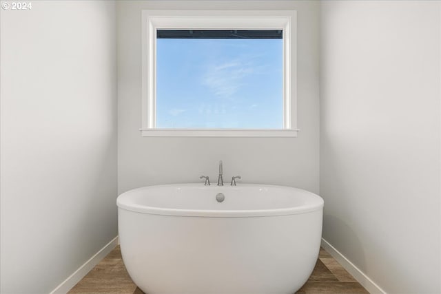 bathroom with a tub and wood-type flooring