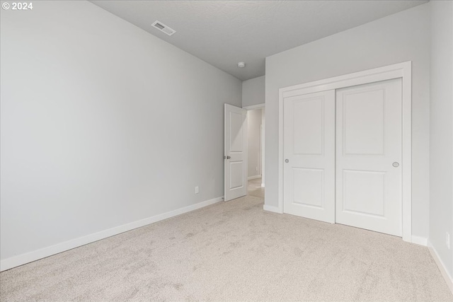 unfurnished bedroom with a closet and light colored carpet