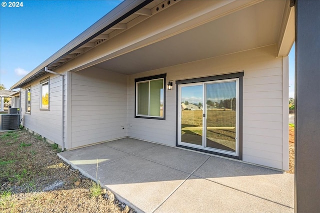 view of exterior entry featuring a patio area and central AC unit