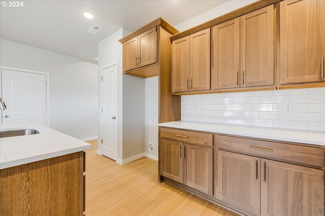 kitchen with sink, light wood-type flooring, and tasteful backsplash