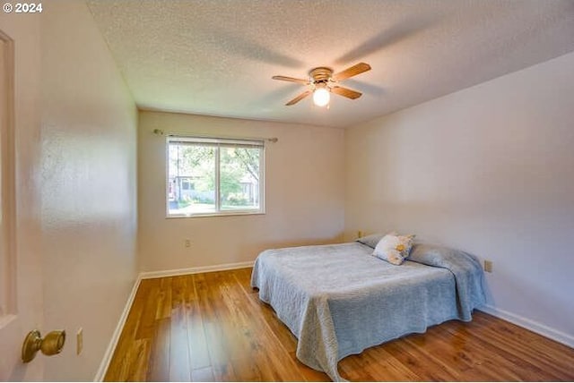 bedroom with ceiling fan, light hardwood / wood-style floors, and a textured ceiling