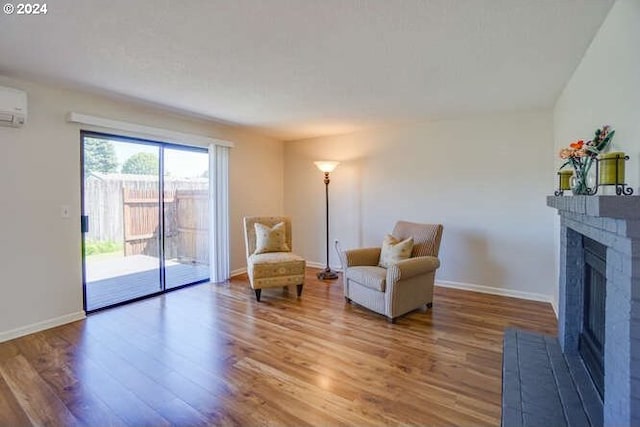 living area featuring hardwood / wood-style floors and a wall unit AC