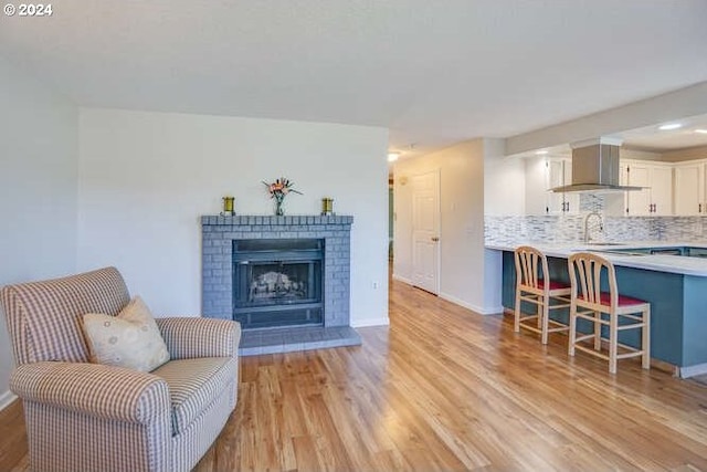 interior space featuring a brick fireplace, sink, and light wood-type flooring