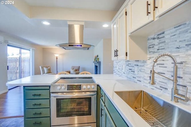 kitchen featuring island exhaust hood, kitchen peninsula, stainless steel electric stove, sink, and white cabinets