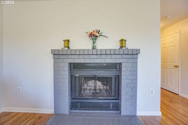 details featuring hardwood / wood-style flooring and a brick fireplace