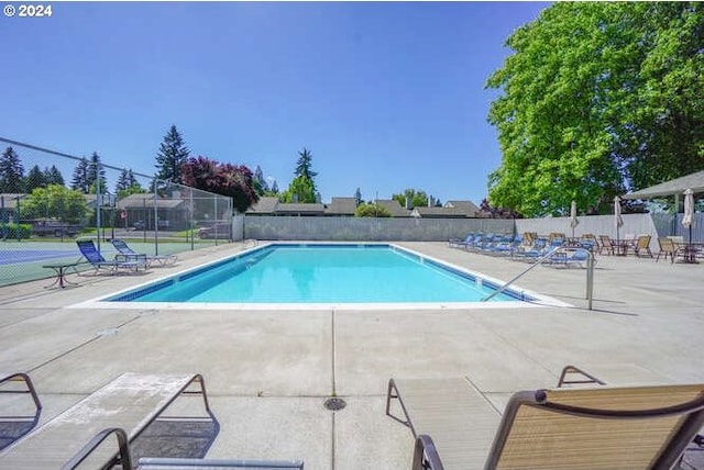 view of swimming pool with tennis court and a patio