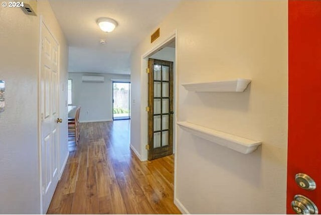 corridor featuring a wall mounted air conditioner and hardwood / wood-style flooring