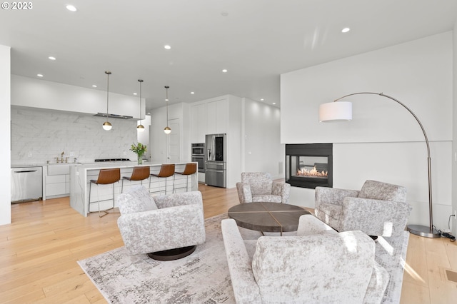 living room featuring light hardwood / wood-style floors, sink, and a multi sided fireplace