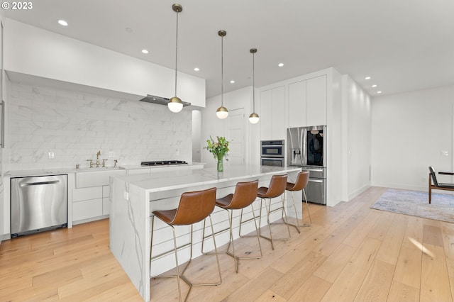 kitchen with a spacious island, stainless steel appliances, light hardwood / wood-style flooring, and white cabinets