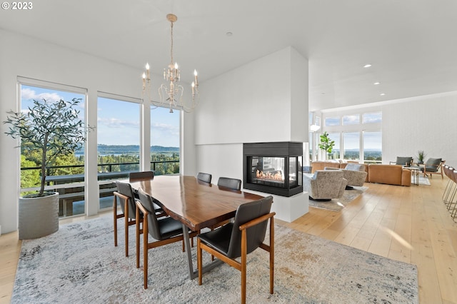 dining area featuring a wealth of natural light, a multi sided fireplace, a chandelier, and light hardwood / wood-style flooring