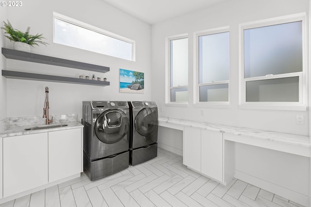 washroom featuring sink, independent washer and dryer, and cabinets