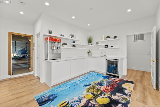 kitchen featuring wine cooler, sink, white cabinets, and light hardwood / wood-style floors