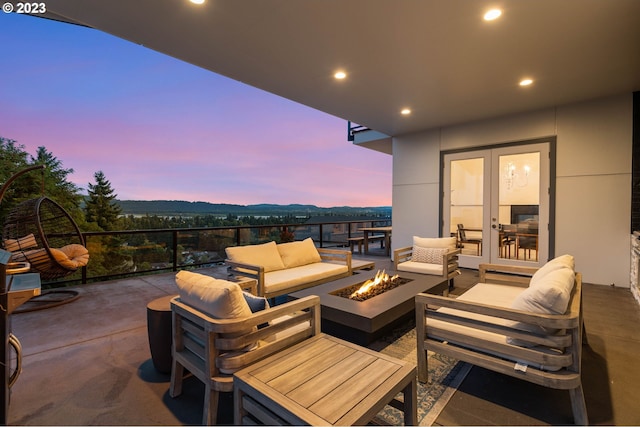 patio terrace at dusk with french doors, a mountain view, and an outdoor living space with a fire pit