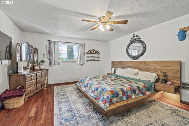 bedroom featuring a textured ceiling, dark wood-type flooring, and ceiling fan