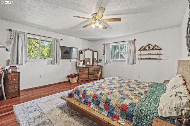 bedroom with wood-type flooring, multiple windows, ceiling fan, and a textured ceiling