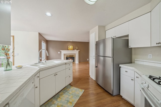 4135 SW Brugger St, Portland, OR 97219 - kitchen featuring tile counters, white appliances, white cabinetry, light wood finished floors, and recessed lighting