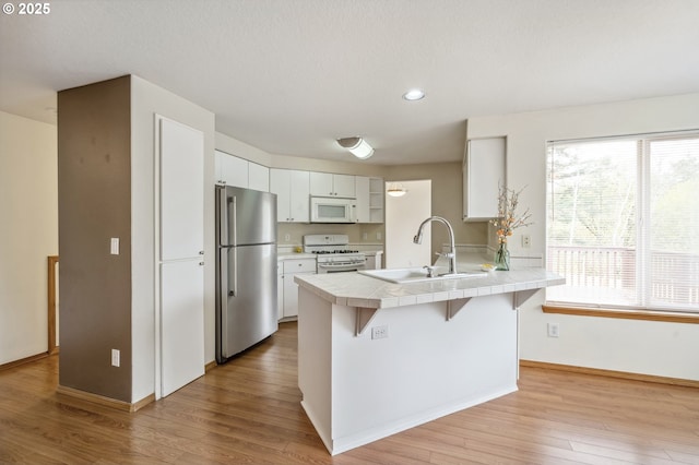 4135 SW Brugger St, Portland, OR 97219 - kitchen with white appliances, tile countertops, a peninsula, white cabinets, and light wood finished floors