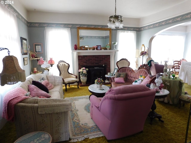 carpeted living room with a brick fireplace, a chandelier, and a healthy amount of sunlight