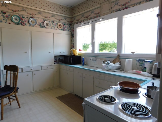 kitchen featuring white cabinetry, range with electric stovetop, and sink