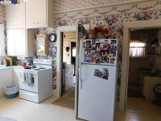 kitchen with white appliances, white cabinetry, sink, and washer / clothes dryer