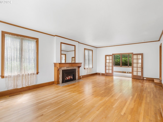 unfurnished living room featuring a fireplace, crown molding, and light wood-type flooring