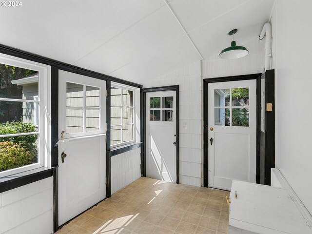 entryway featuring a wealth of natural light, vaulted ceiling, and light tile patterned flooring