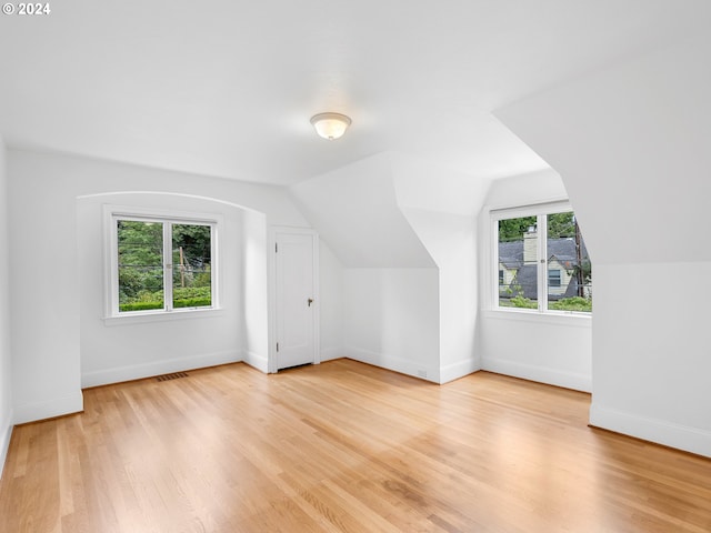 bonus room with a wealth of natural light, vaulted ceiling, and light wood-type flooring