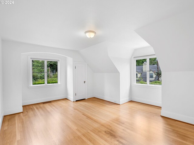 additional living space with light hardwood / wood-style flooring and lofted ceiling