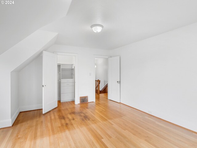 additional living space with light hardwood / wood-style floors and vaulted ceiling