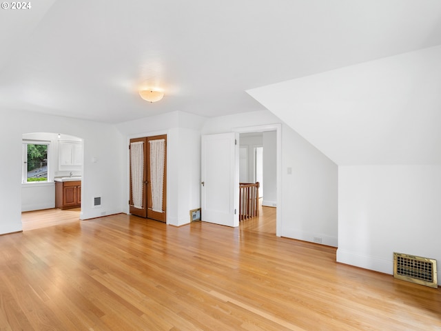 additional living space with light hardwood / wood-style flooring and lofted ceiling