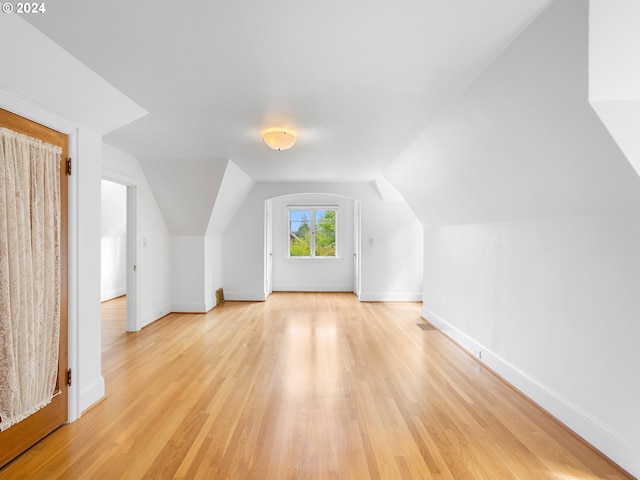 additional living space with light hardwood / wood-style flooring and lofted ceiling