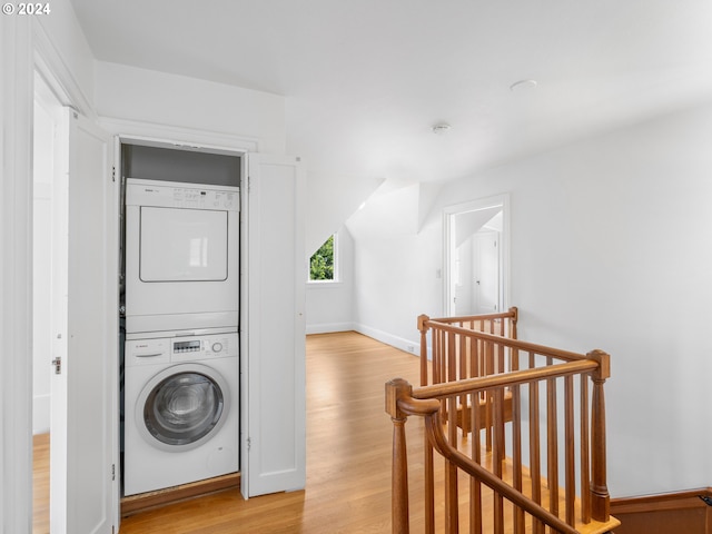 washroom with stacked washer / drying machine and light hardwood / wood-style flooring