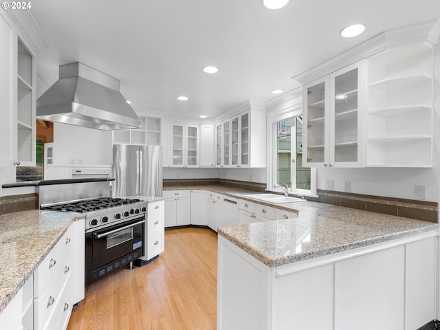 kitchen with stainless steel fridge, light hardwood / wood-style floors, wall chimney range hood, and light stone counters