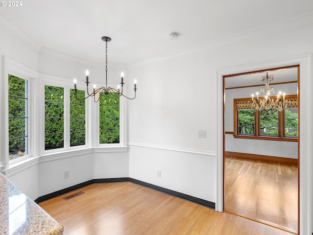 unfurnished dining area with light wood-type flooring, crown molding, and a chandelier