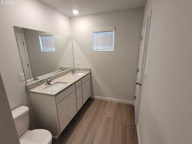 bathroom with baseboards, a sink, toilet, and wood finished floors