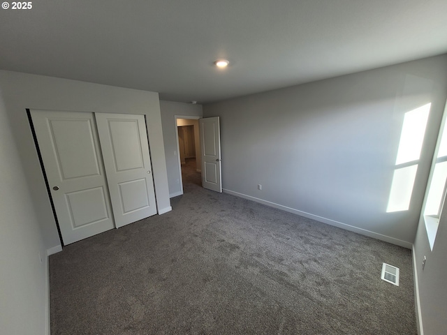 unfurnished bedroom featuring carpet floors, a closet, visible vents, and baseboards