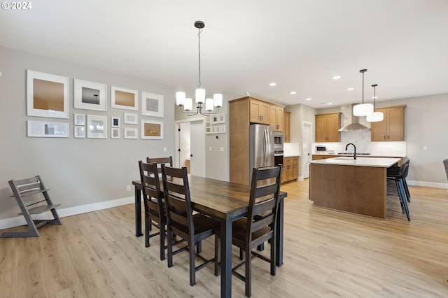 dining room featuring sink, an inviting chandelier, and light hardwood / wood-style flooring