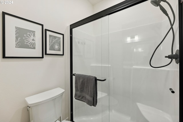 bathroom with a shower with door and toilet