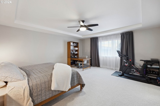 carpeted bedroom featuring ceiling fan and a tray ceiling