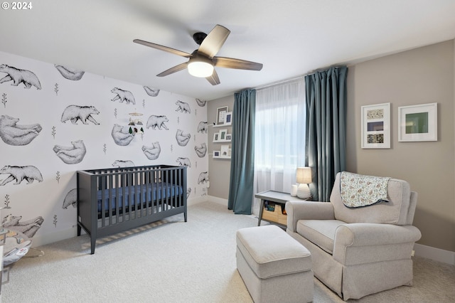 carpeted bedroom with a crib and ceiling fan