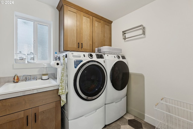 clothes washing area featuring cabinets, a healthy amount of sunlight, washer and dryer, and sink