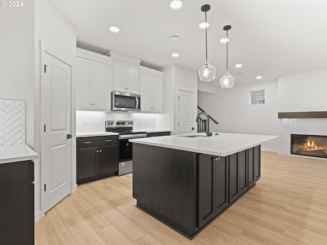 kitchen with appliances with stainless steel finishes, light wood-type flooring, pendant lighting, and sink