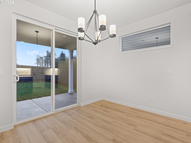 unfurnished dining area featuring wood-type flooring and a chandelier