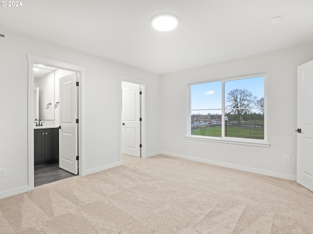 unfurnished bedroom featuring light carpet and ensuite bath