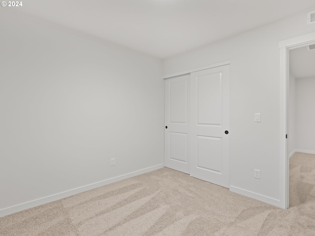 unfurnished bedroom featuring light carpet and a closet