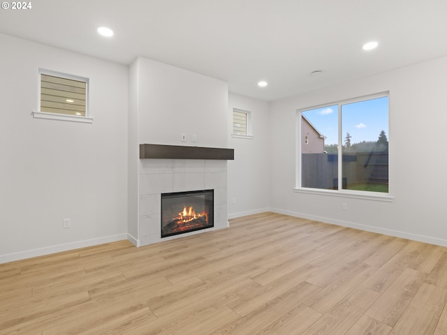 unfurnished living room featuring a tile fireplace and light wood-type flooring