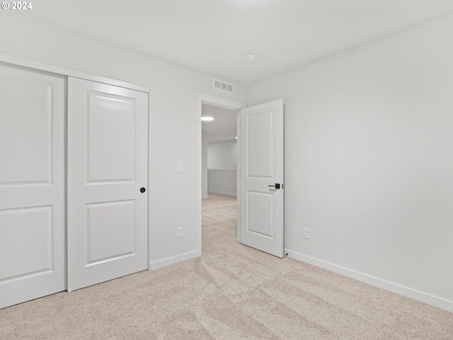 unfurnished bedroom with light carpet and a closet