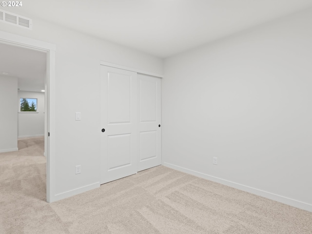 unfurnished bedroom with light carpet and a closet